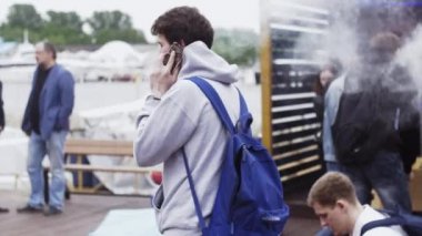 Saint Petersburg, Rusya - 28 Mayıs 2016: Vapers sokak festivalinde insan elektronik sigara içiyor. Telefonda konuşma.