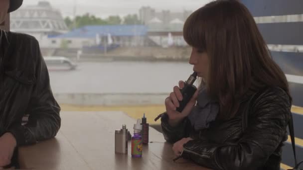 SAINT PETERSBURG, RUSIA - 28 DE MAYO DE 2016: Chica exhala vapor del cigarrillo electrónico en una tienda especializada en la calle. Vapers. — Vídeos de Stock