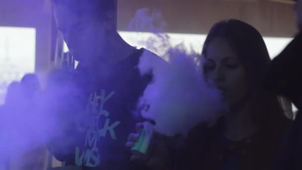 SAINT PETERSBURG, RÚSSIA - 28 de maio de 2016: Menino e menina fumam cigarro eletrônico. Clube Nocturno. Holofotes coloridos. Ceifeiras . — Vídeo de Stock