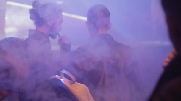 Αγία Πετρούπολη, Ρωσία - 28 Μαΐου 2016: Άνδρες καπνίζουν ηλεκτρονικό τσιγάρο σε νυχτερινό κέντρο διασκέδασης γεμάτο από ατμού. Προβολείς. Ατμιστες. — Αρχείο Βίντεο