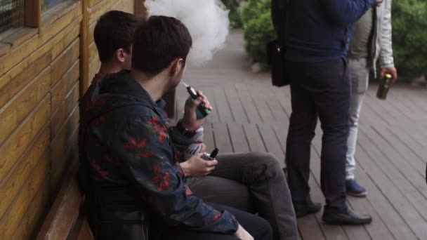 サンクトペテルブルク、ロシア - 2016年5月28日:男性のグループは、ベンチに座って電子タバコを吸います。ヴァッパーズ・フェスティバル蒸気 — ストック動画