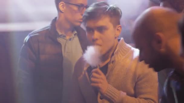 САЙНТ-ПЕТЕРБУРГ, РОССИЯ - 28 мая 2016 года: Молодой человек курит электронную сигарету в специализированном магазине. Вэйп. Пар. Spotlight — стоковое видео