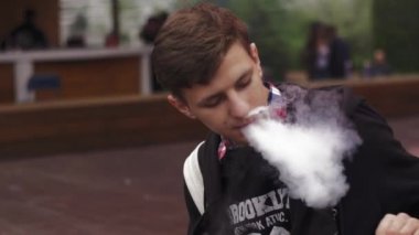 Sokakta genç çocuk duman elektronik sigara. Vaper. Buhar çok. Alt kültür