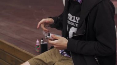 Genç çocuk sokakta elektronik sigara içine sıvı dökün. Vaper. Sigara içen. Buhar
