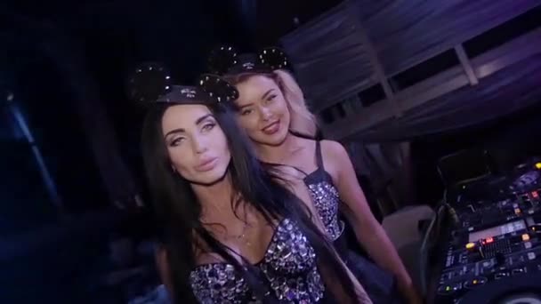 Dj girl and MC girl in mouse ears touch breast at turntable in club. Slow motion — Stock Video