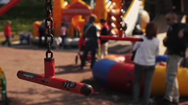 Balançoire rouge au foyer. Beaucoup d'enfants jouent sur l'aire de jeux. Jour d'été. Festival — Video