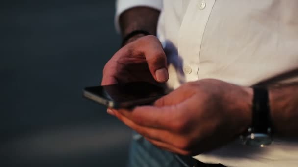 Homem adulto usando smartphone preto na rua. Olha. Tecnologia. Telefone. Tocando — Vídeo de Stock