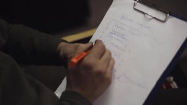 Adam oturup koltuğu altı çizili sözcükler listesinde mavi kalem yanında ağıl içinde kağıt üzerinde