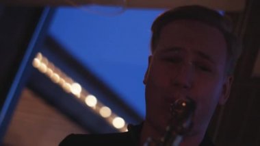 Adam parti gece kulübünde saksafon oynamak. Performans. Kamera bak. Tezahürat.