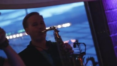 Adam altın saksafon parti gece kulübünde üzerinde oynamak. Performans. DJ pikap.