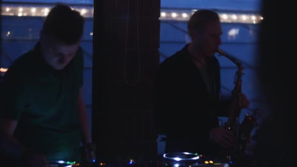 DJ spinnen bij draaitafel. Man play saxofoon. Feest in nachtclub. Silhouetten — Stockvideo