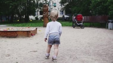 Şortu olan küçük çocuk yaz günü oyun alanında yürür. Mutluluk. Çocukluk