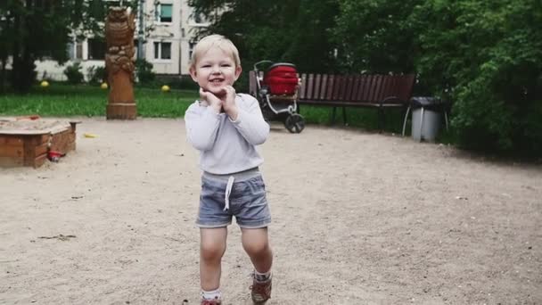 Menino em shorts caminha no playground no dia de verão. Sorri. Infância. Feliz. — Vídeo de Stock