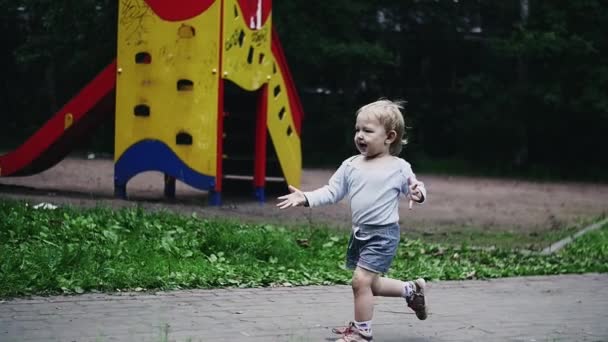 Blonder kleiner Junge läuft auf Spielplatz zu Mutter. Tauben im Sommerpark. Kindheit — Stockvideo