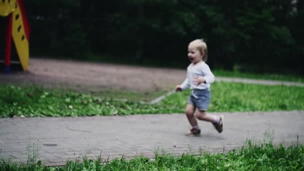 Ευτυχισμένο αγοράκι που τρέχει στην παιδική χαρά στο καλοκαιρινό πάρκο. Ιπτάμενα περιστέρια. Μητέρα — Αρχείο Βίντεο