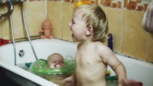 Liten pojke njuter av vatten i badkaret. Baby simma i uppblåsbar cirkel. Stänk. — Stockvideo