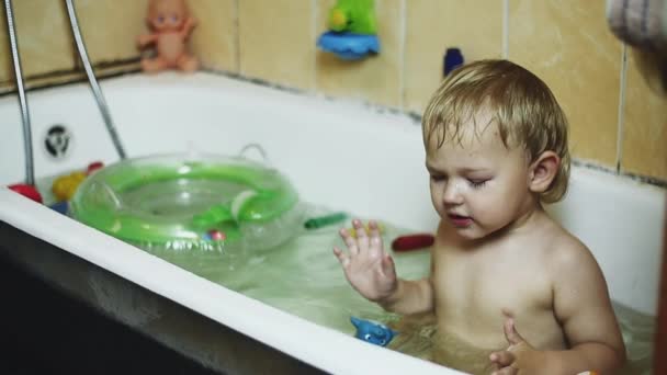 Мальчик плавает в ванной. Надувной круг, игрушки. Счастье. Купание — стоковое видео