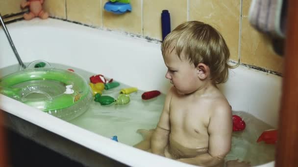 Niño sentado en la bañera. Círculo inflable, juguetes. Disfrutando el baño. Niño. — Vídeos de Stock