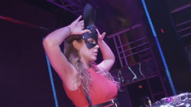 Dj girl in hare mask, red dress dance at turntable in nightclub. Wave hands — Stock Video