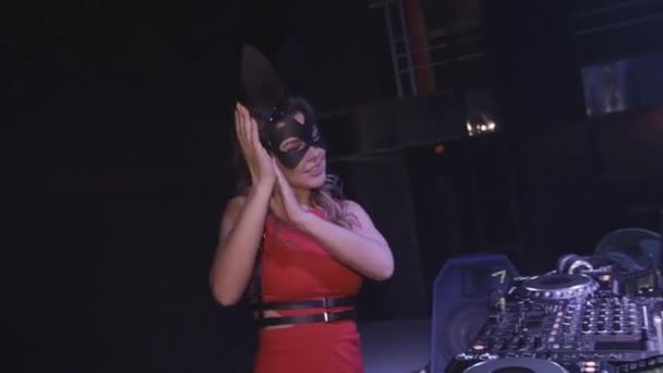 DJ dziewczyna w zając maska, czerwona sukienka klaskać w ręce o gramofonu w klubie nocnym. Taniec — Wideo stockowe