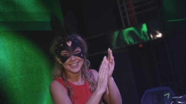 Fröhliches DJ-Mädchen in Hasenmaske, rotes Kleid klatscht in die Hände am Plattenteller im Nachtclub. — Stockvideo