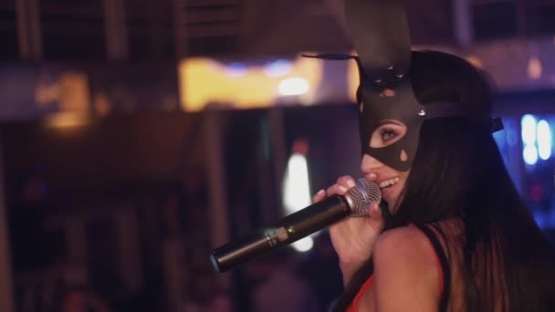 Brunette MC-jente i svart hare-maske opptrer på scenen på nattklubben. Rumpe. Vis – stockvideo