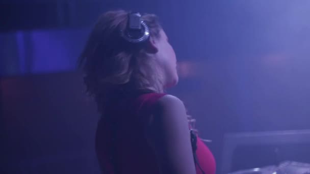 DJ-Mädchen mit Kopfhörern heben die Hand zum Tanz am Plattenteller im Nachtclub. Stroboskop. Mischen — Stockvideo