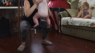 Genç anne elinde bebekle ağız kavgası yapmak. Koltukta oturan oğlu. Daire