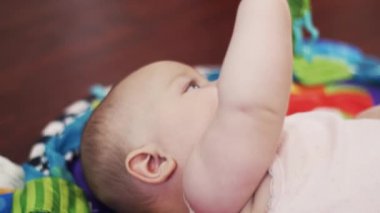 Portre küçük bebek oyuncakları ile oynarken renkli halı üzerinde yalan. Annelik