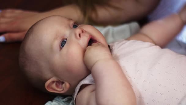 Jonge moeder liggen op de vloer met kleine baby, houden de handen in de mond. Appartement. — Stockvideo