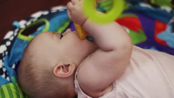 El pequeño bebé yace en la cuna jugando con juguetes, sosteniéndose en la boca. Lindo. Maternidad . — Vídeo de stock