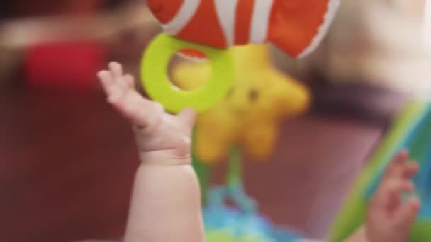 Händerna på lilla barnet ligga i spjälsängen leker med hängande leksak. Moderskap. Barn — Stockvideo