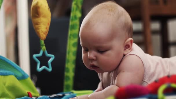 Schattige kleine baby liggen op kleurrijke ontwikkelen kinderen tapijt. Speelgoed. Spelen — Stockvideo