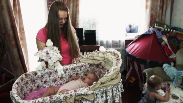 Jovem mãe brincar com o bebê pequeno mentira em berço bonito. Maternidade. Menino no sofá . — Vídeo de Stock