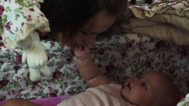 Jovem mãe brincar com o bebê pequeno mentira em berço bonito. Mãos à obra. Felicidade . — Vídeo de Stock