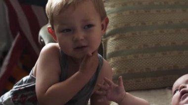 Küçük sarışın çocuk oyun Divan bebek yalanla. Çocuklar. Seviyorum. Kardeşim. Kız kardeşi.