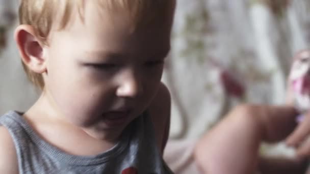 Giovane madre vestire bambino, piccolo figlio davanti alla telecamera. La maternità. Famiglia . — Video Stock