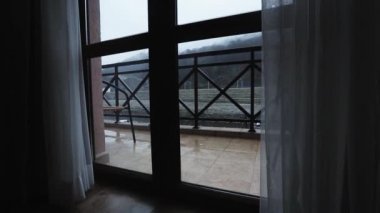 Damla yağmur yağmaya verandada pencereden dışarı görüntüleyin. Gri gökyüzü. Pencereden dışarı dağlar.