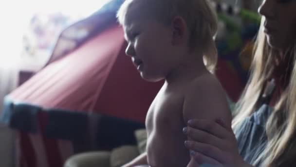 Giovane madre vestire piangendo piccolo figlio biondo sul divano. La maternità. Camicia. Bambino. — Video Stock