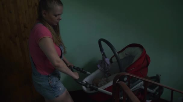 Young mother put down baby carriage from stairs. Motherhood. Little son. Baby — Stock Video