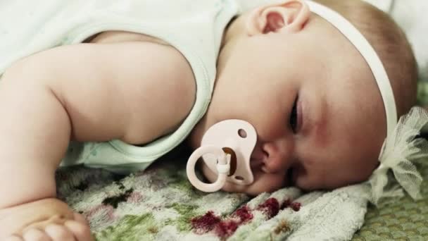 Schattige kleine baby lig op de Bank met baby dummy. Cute. Kijken in de camera. — Stockvideo