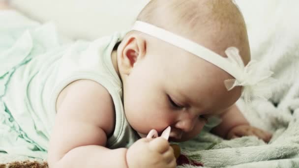 Adorable bebé se acuesta en el sofá poner maniquí bebé en la boca. Lindo. Infancia . — Vídeo de stock