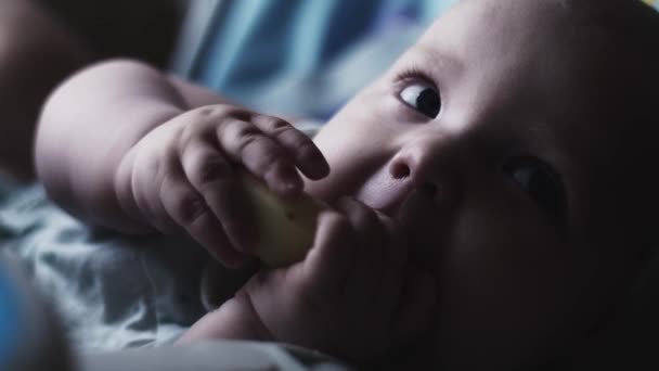 Adorable bebé lindo sentarse a la mesa de los niños comiendo pera. Ojos azules. Mira en la cámara — Vídeo de stock