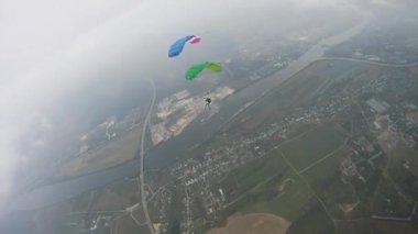Yeşil alan üzerinde gökyüzünde uçan paraşütçü. Aşırı aktif spor. Tandem.