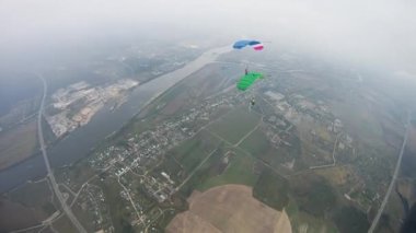 Skydivers renkli paraşüt yeşil alan üzerinde uçan ile nehir. Aşırı spor