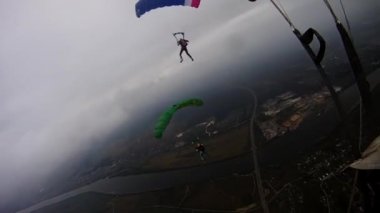 Skydivers renkli paraşüt ile bulutlu gökyüzü yeşil alanı üzerinden uçmak. Aşırı