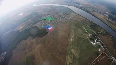 Yeşil alan üzerinde gökyüzü dengede renkli paraşüt ile skydivers. Nehir.