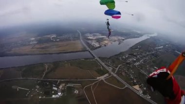 Skydivers yeşil alan üzerinde gökyüzü dengede renkli paraşüt ile tandem.