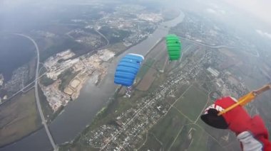 Skydivers yeşil alan üzerinde gökyüzünde uçmak. Renkli paraşüt. Aşırı. Denge.