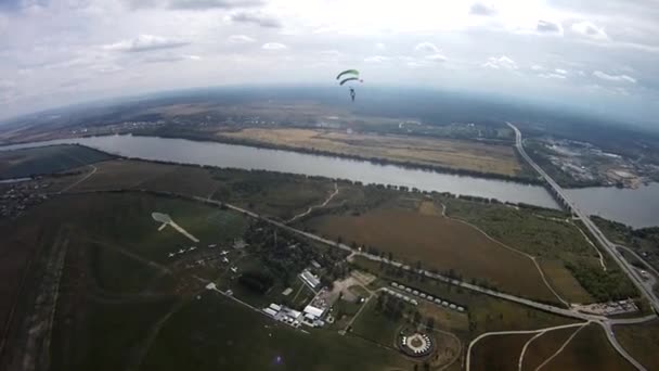 Skydivers a sobrevoar o campo verde, rio. Desporto ativo extremo. Pára-quedas . — Vídeo de Stock